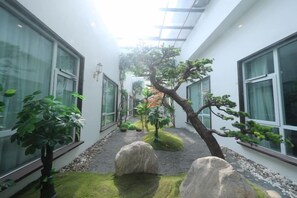 Un bâtiment moderne doté de grandes fenêtres, d’un chemin central et d’une grande variété de plantes.