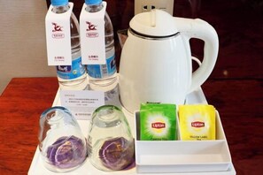 Una mesa con un hervidor blanco, dos botellas de agua, dos vasos y bolsitas de té Lipton.