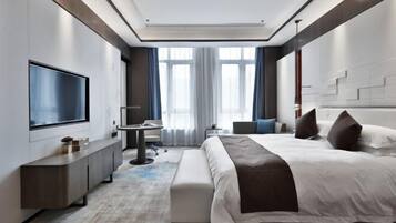 Une chambre d’hôtel moderne dotée d’un grand lit, d’un bureau, d’une télévision à écran plat et d’un coin salon.