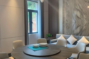 A modern dining area with a round table, white chairs, and a sofa with cushions.