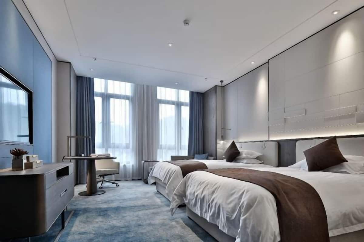 Moderni hotellihuone, jossa on suuri sänky, työpöytä ja oleskelualue.