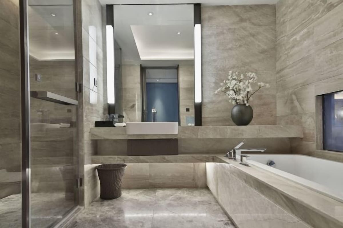 Un baño moderno con un espejo grande, una bañera independiente y un tocador con lavamanos.