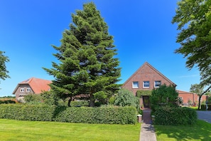 A residential building with a brick facade, a red roof, and a well-maintained lawn.