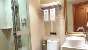 Ein Badezimmer mit Duschkabine, Toilette und Waschbecken mit Spiegel darüber.