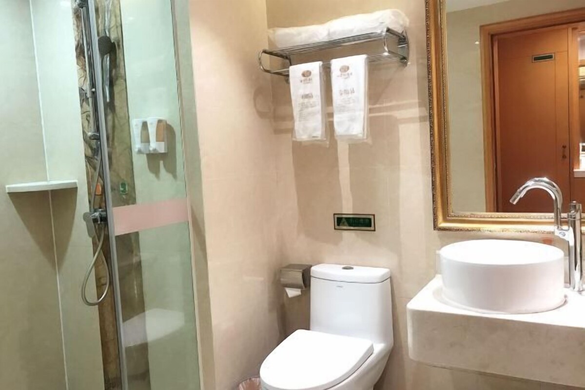 A bathroom with a glass shower enclosure, a toilet, and a sink with a mirror above it.