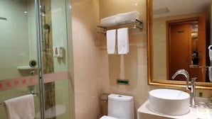 Ein Badezimmer mit einer gläsernen Duschkabine, einem weißen Waschbecken und einem großen Spiegel.