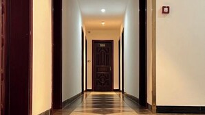 Um corredor com piso estampado leva a uma porta com desenho geométrico.