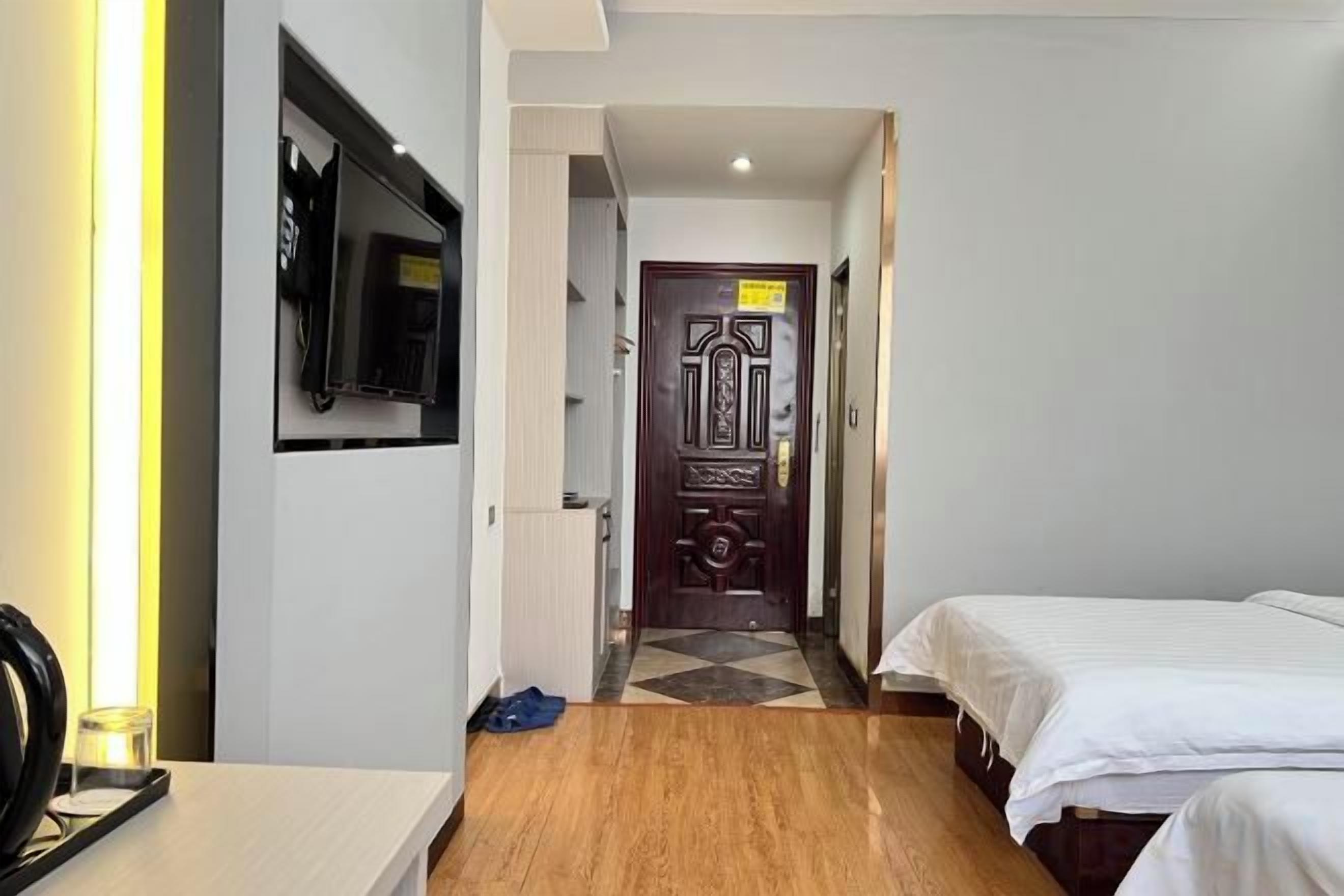 Habitación de hotel con una cama, un televisor montado en la pared y una puerta con un letrero.