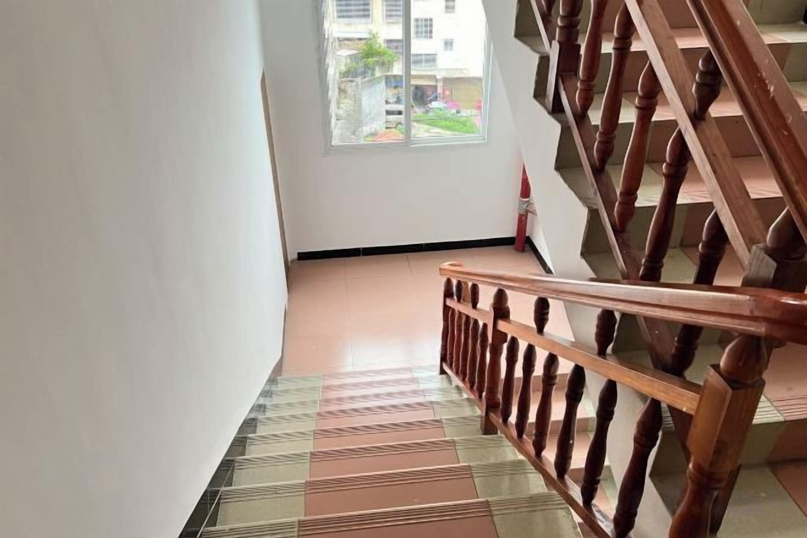 A staircase with a wooden handrail and a patterned floor.