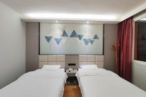 Habitación de hotel con dos camas, una obra de arte grande colgada en la pared, una mesita de noche y una ventana con cortinas.