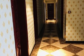 A hotel hallway with patterned wallpaper, checkered flooring, and a door at the end. - 7 xing Ge Business Hotel (Xing'an County)