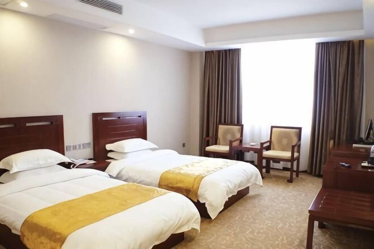 Una habitación de hotel con dos camas, un escritorio, una silla y un televisor.