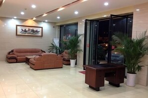 A lobby with a sofa set, a desk, and potted plants.