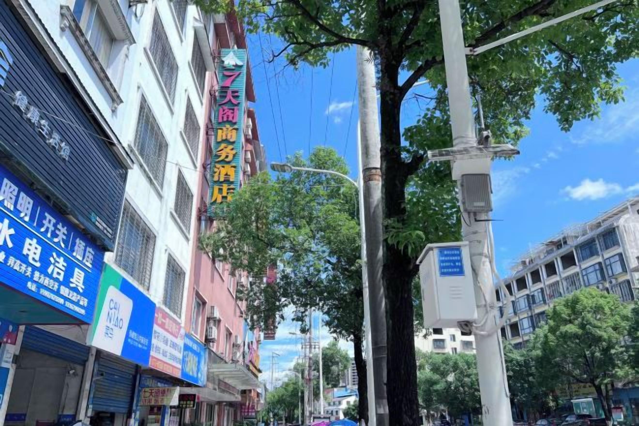 A street with buildings, trees, and a clear sky.