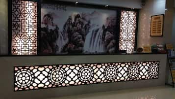 A reception area with a large screen displaying a waterfall painting, decorative screens, and a reception desk.