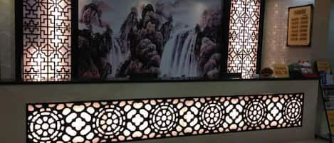 A reception area with a large screen displaying a waterfall painting, decorative screens, and a reception desk.