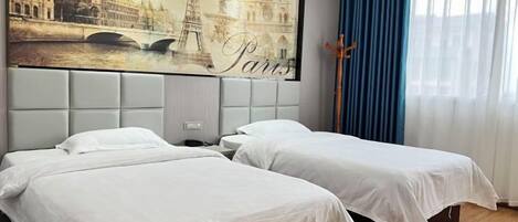 A hotel room with two beds, a large window with blue curtains, and a wall mural of Paris landmarks.