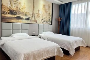 Habitación de hotel con dos camas, un ventanal con cortinas azules y un mural en la pared con monumentos de París.