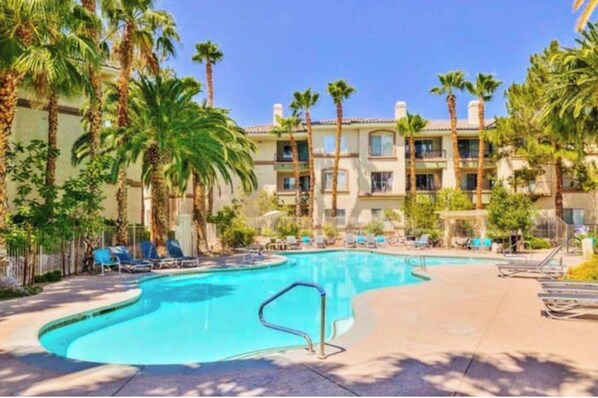 Relax by the resort pool surrounded by palm trees and lounge chairs.