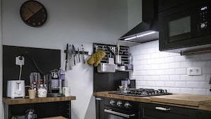 Eine moderne Küche mit Mikrowelle, Herd, Backofen und verschiedenen Küchenutensilien an der Wand.