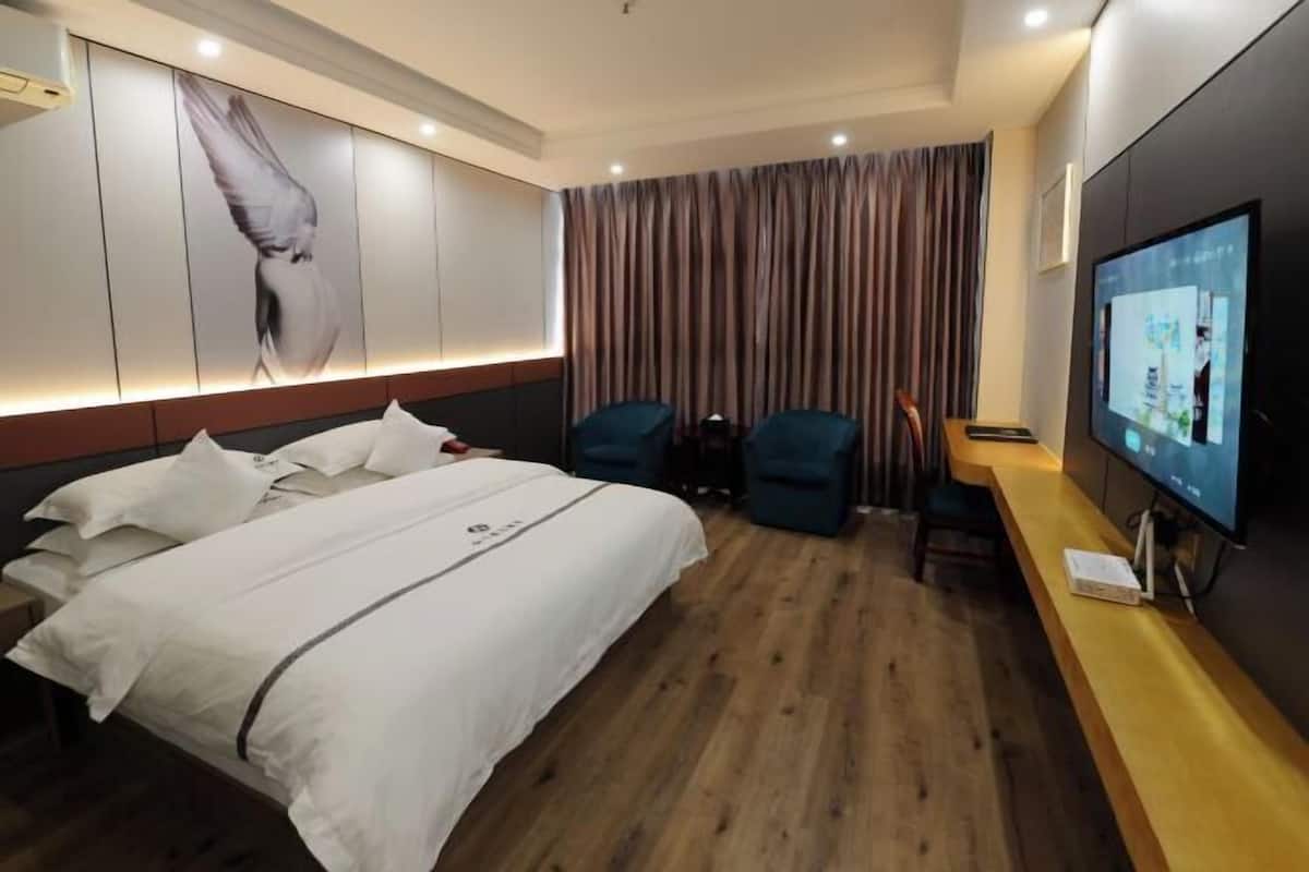 A hotel room with a bed, a TV, a desk, and a chair.