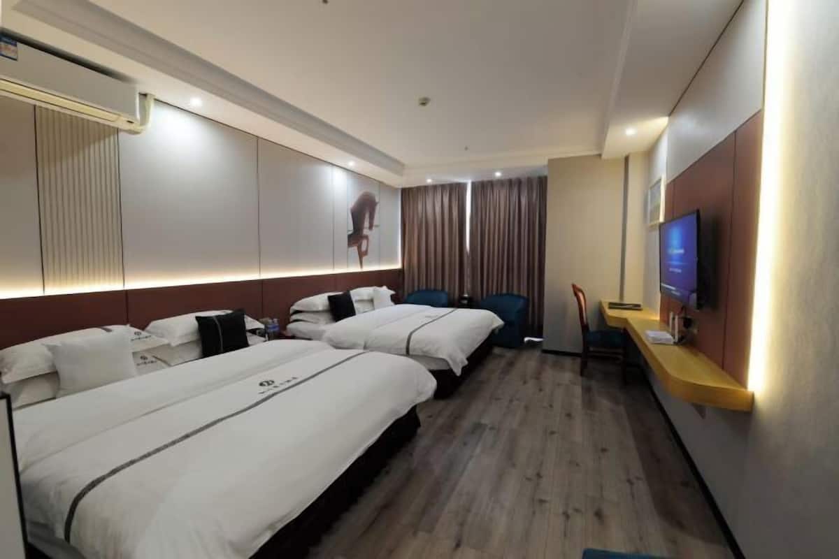 A hotel room with two beds, a TV, a desk, and a curtain.