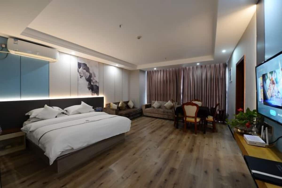 A modern hotel room with a large bed, a sofa, a TV, and a desk with a computer.