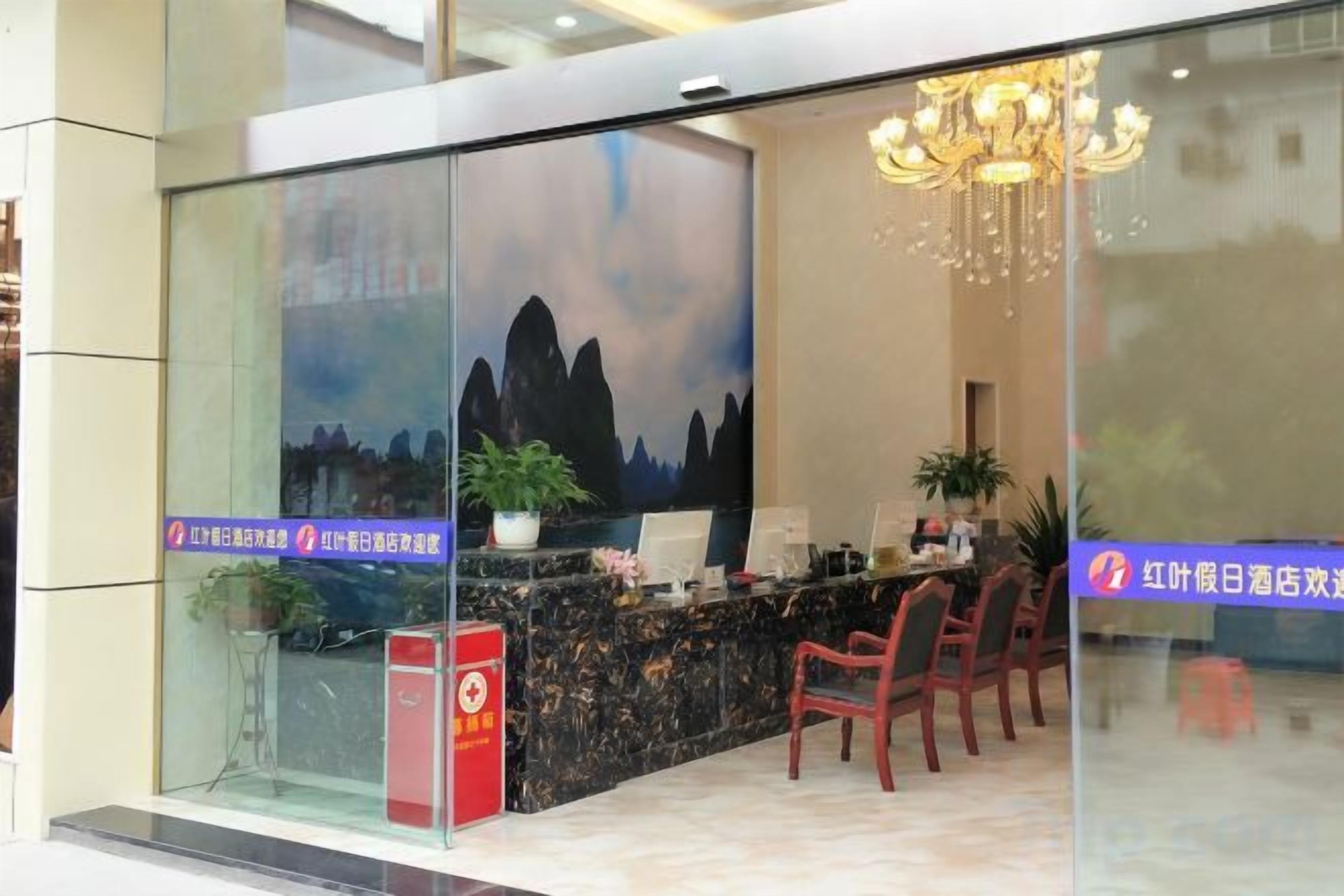 A hotel reception area with a glass partition, a reception desk, and a chandelier.