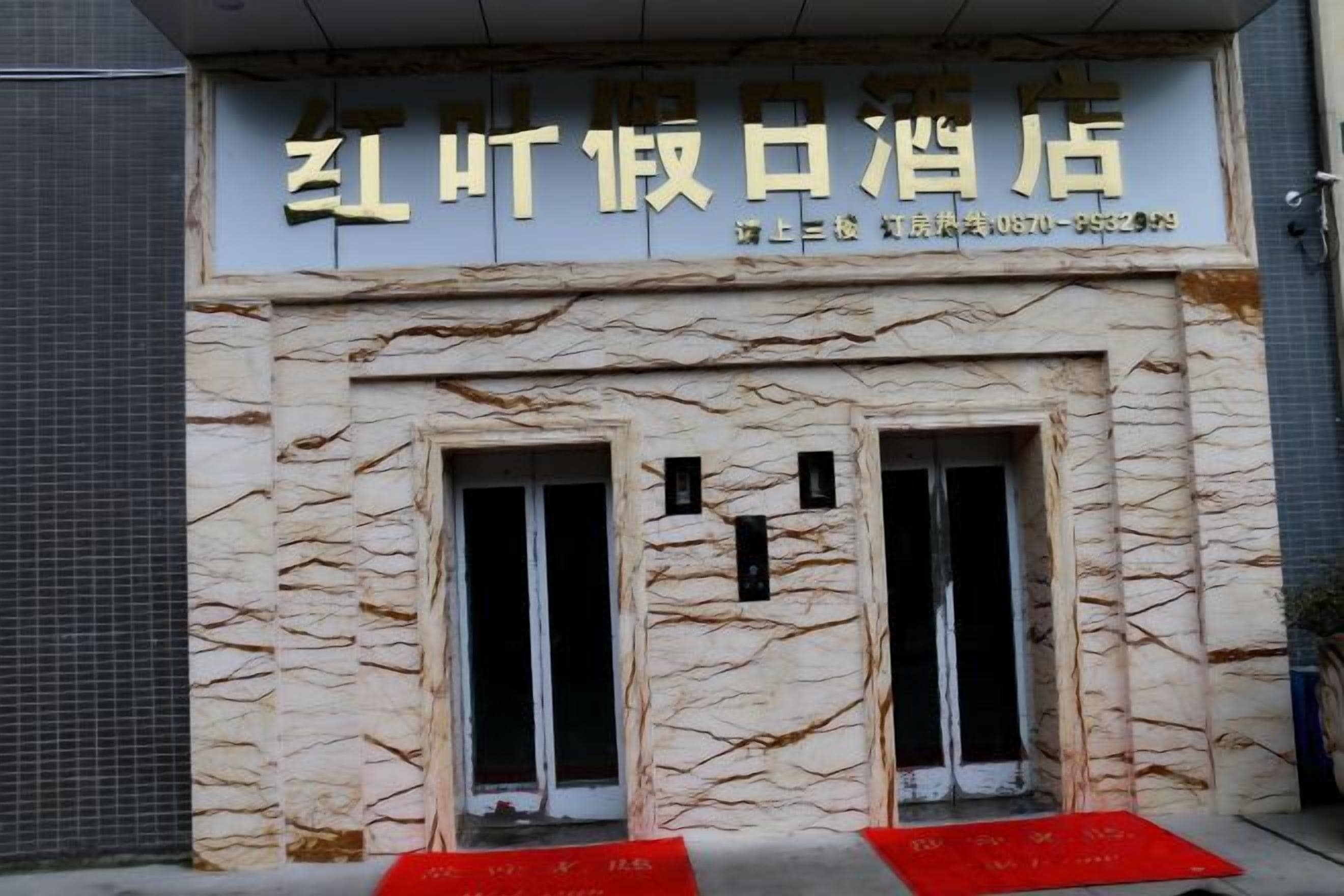 A building facade with a sign indicating a restaurant or cafe. There are two visible windows with black frames and a red mat at the entrance.