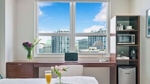 Une chambre d’hôtel équipée d’un lit, d’un bureau avec un ordinateur portable, d’une machine à café et d’un mini-bar.