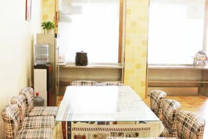 A room with a long table and plaid chairs, a water dispenser, and a window with a view. - Tangla Town Holiday Hotel (Dehui)