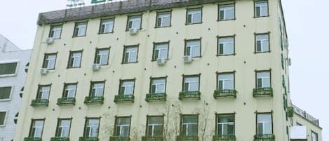 A multi-story hotel with a flat facade, multiple balconies, and a sign at the top.