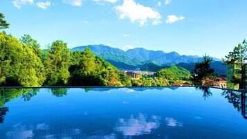 Visão nítida de uma piscina refletindo a paisagem ao redor, incluindo árvores e montanhas distantes.
