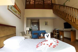 A hotel room with a bed, a blue sofa, a desk, and a staircase.