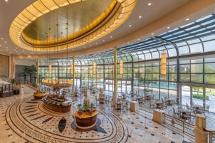 Un hall amplio con una zona de estar circular central, ventanas grandes y un diseño de techo moderno.