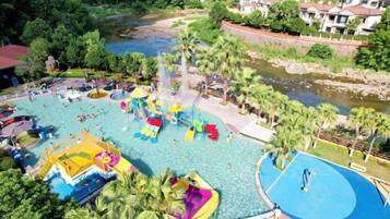 A water park with multiple slides and pools, surrounded by greenery and a river.
