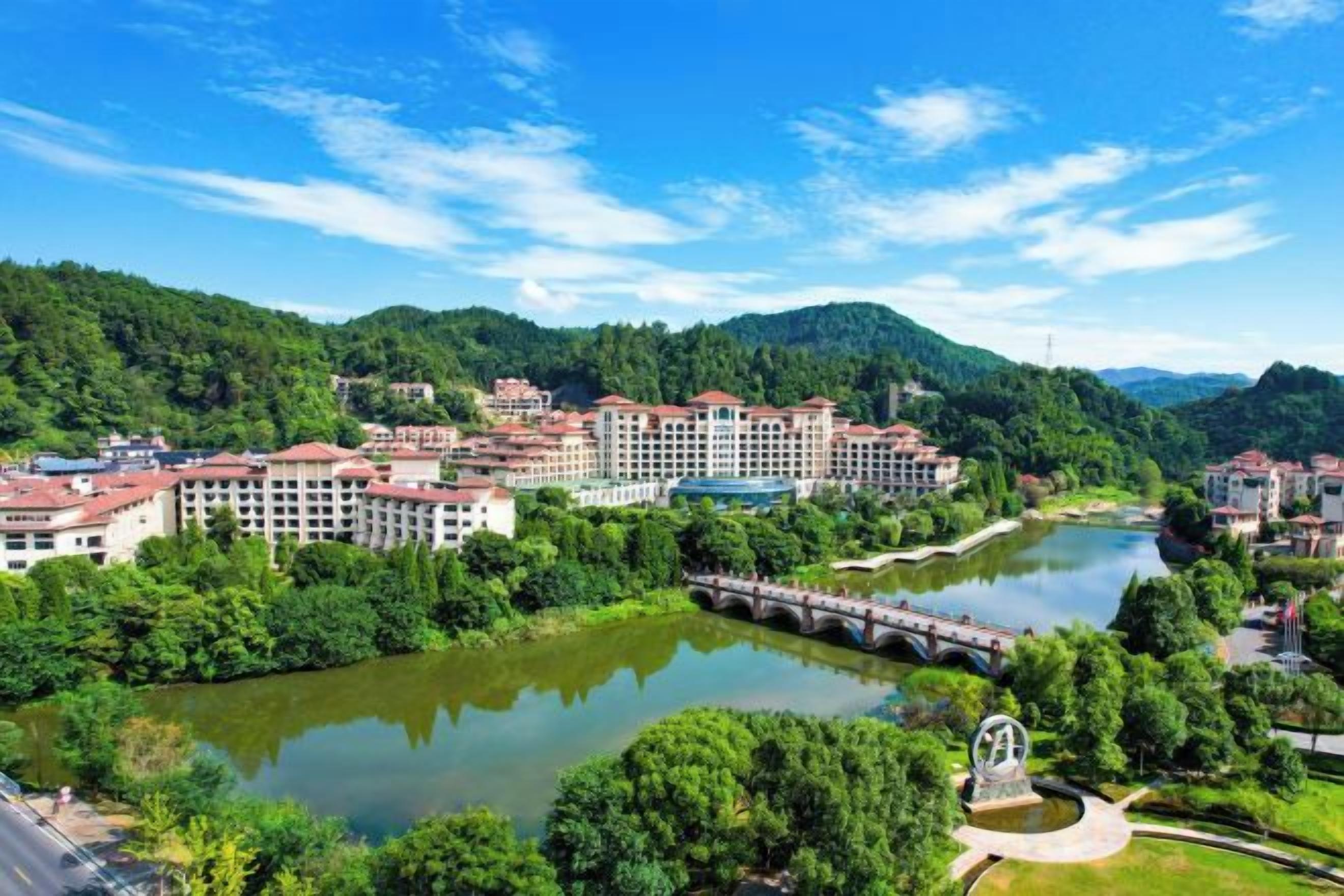 A riverside town with buildings, a bridge, and a statue.