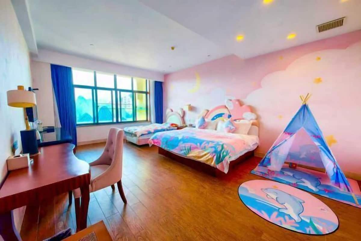 A bedroom with a bed, a desk, a chair, a window, and a tent-like structure.
