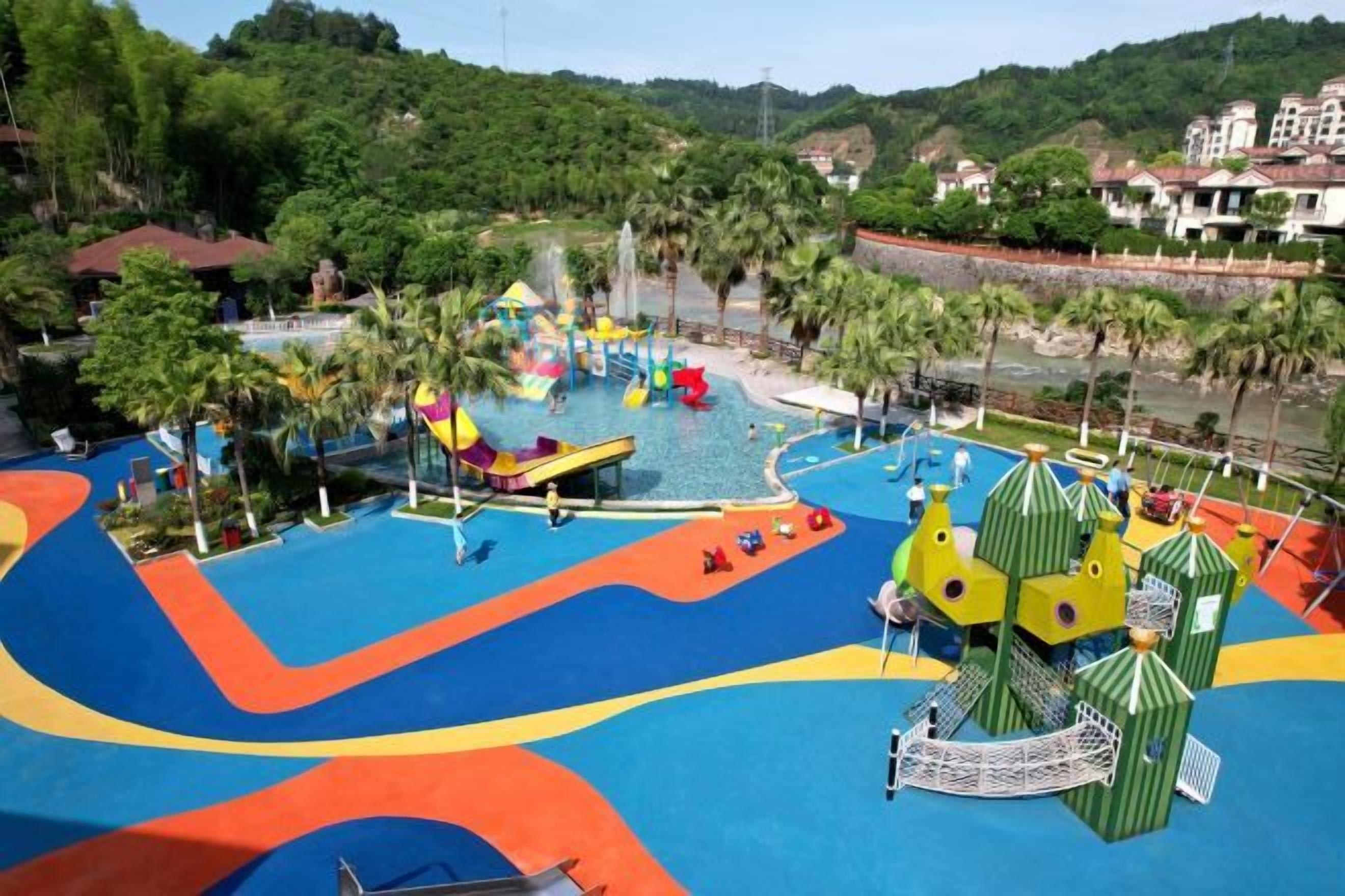 A water park with slides and pools, surrounded by greenery and buildings.