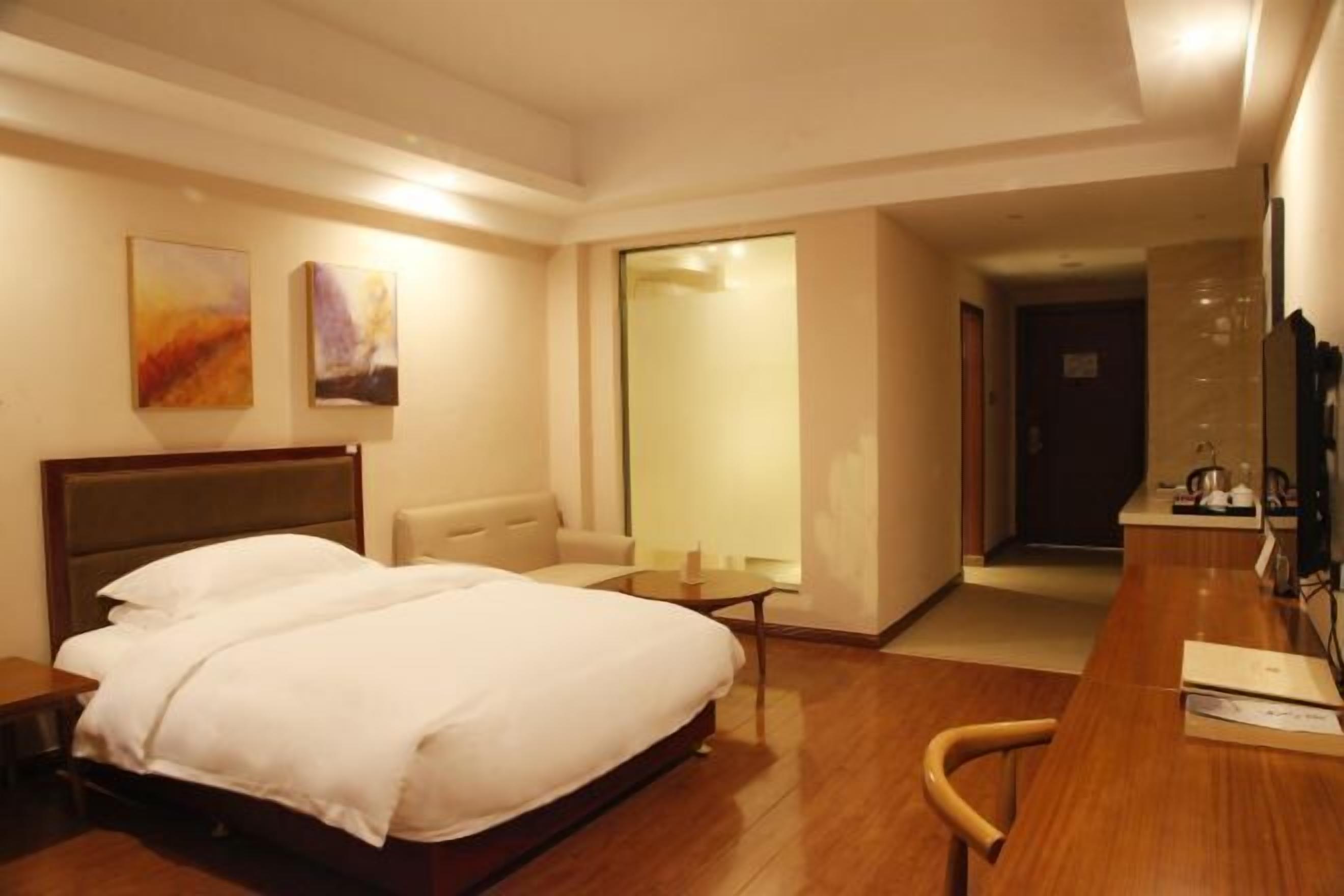 Et hotelværelse med seng, skrivebord, stol, lille bord og sofa.