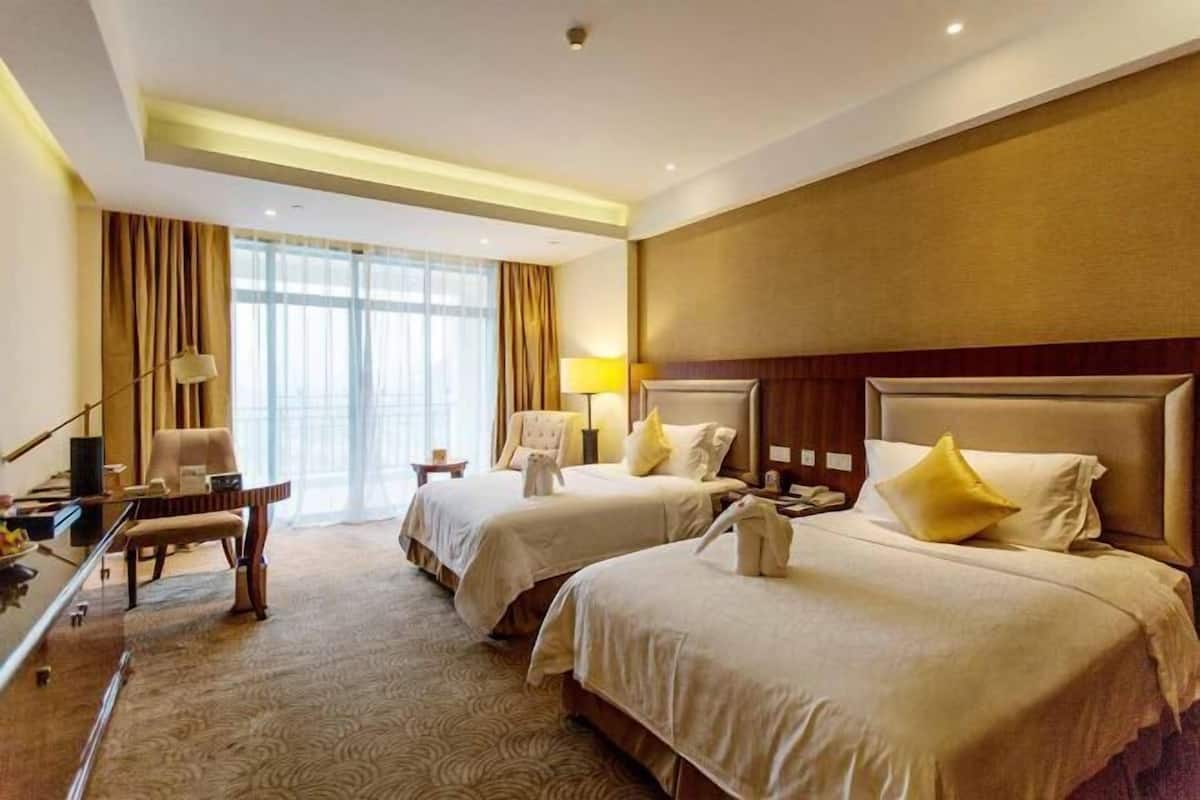 A hotel room with two beds, a desk, and a chair.