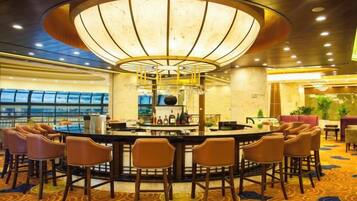 A bar area with a circular bar, multiple bar stools, and a central light fixture.