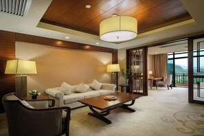 A hotel room with a sofa, armchairs, a coffee table, and a dining area with a table and chairs. - Yichun Grand Metropark Resort (Yichun)