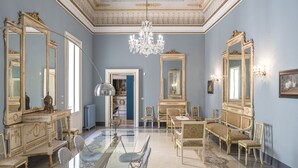 Een statige kamer met sierlijk meubilair, een kroonluchter en grote spiegels.