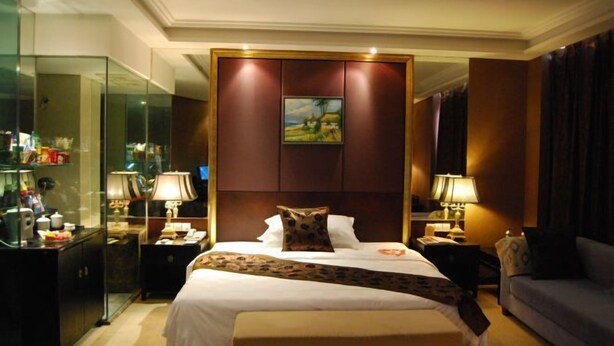 A hotel room with a large bed, bedside tables with lamps, a glass partition, and a painting on the wall. - Minghao Hotel (Chongqing)