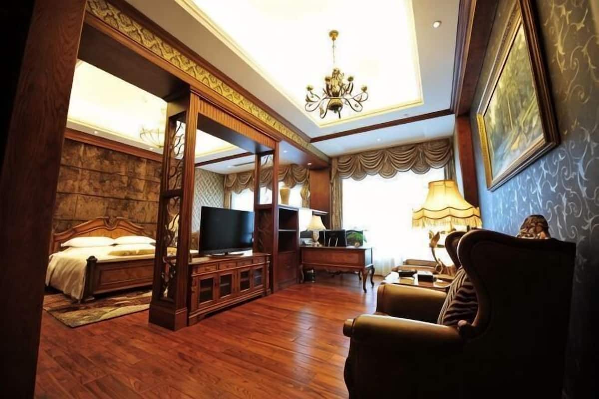 A bedroom with a four-poster bed, a television, a desk with a lamp, and a chair.