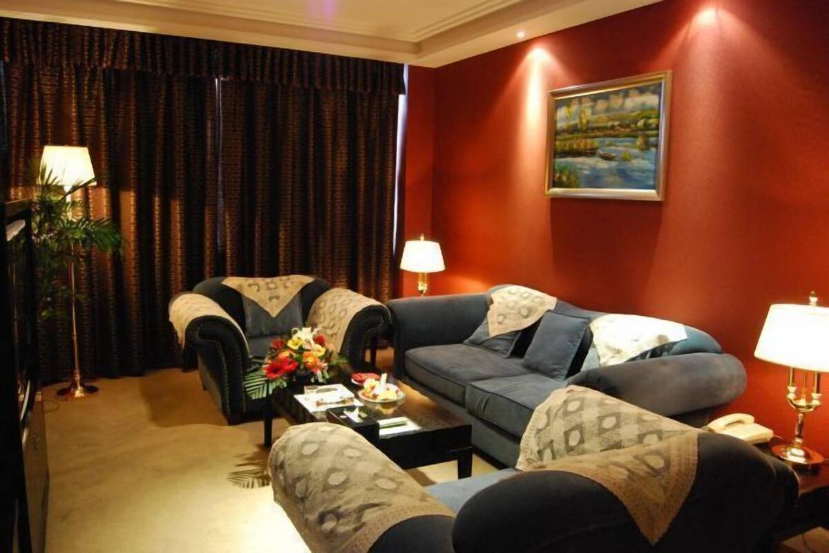 A living room with a sofa set, a coffee table with flowers, and two lamps.