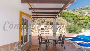 Eine Terrasse im Freien mit Tisch und Stühlen, einem Pool und einer Steinmauer.