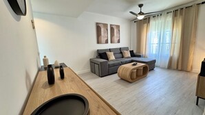 A modern living room with a grey sectional sofa, a wooden coffee table, and a ceiling fan.