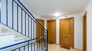 A staircase with a blue railing leading to a landing with three wooden doors.
